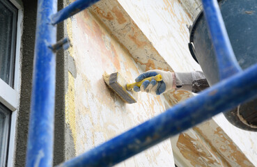 Renovating external house facade wall. A man is applying the primer coat with a brush before...