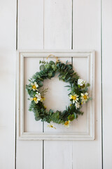 wreath of flowers and greens in a frame on a wooden wall