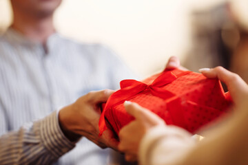 Valentine's Day concept. Close shot of man's and woman's hands presenting gifts to each other at a cafe. A young loving couple celebrating in the restaurant. New normal, winter holidays.