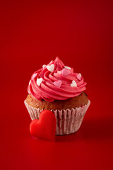 Cupcake decorated with sugar hearts for Valentine's Day on red background