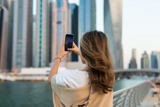 Portrait of young woman take photo on the phone on downtown skycrapers background