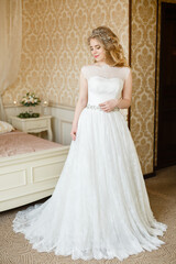 Fototapeta premium Pretty young Bride. Blonde woman with luxurious long curly hair. Boudoir morning of the bride. 