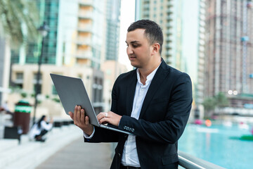 Fototapeta premium Handsome young man working on laptop outdoors. Concept of work life balance.