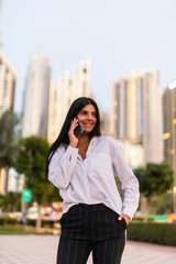 Portrait of a professional business woman smiling with mobile phone outside in the street