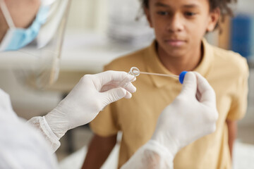 Close up of unrecognizable doctor taking covid swab test from African-American boy in medical clinic