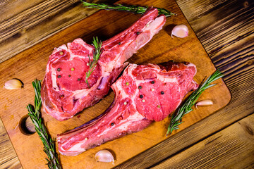 Raw ribeye steak, spices, rosemary and garlic on cutting board. Top view