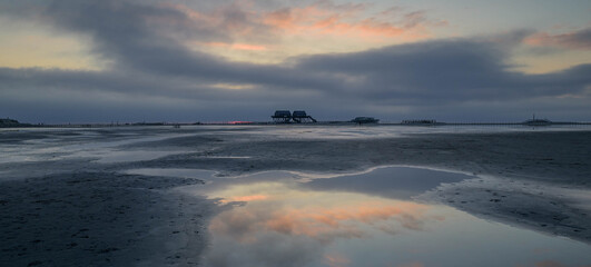 Landscape view of a beach and stilt houses with cloud reflexion in mud flat, St Peter-Ording, North...