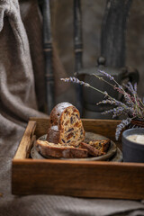 A piece of a sponge or bundt cake with dried fruits on a wooden tray with lavender flowers on a rustic chair. Beautiful desert or breakfast, copy space. Homemade freshly baked pie.