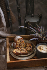 A piece of a sponge or bundt cake with dried fruits on a wooden tray with lavender flowers on a rustic chair. Beautiful desert or breakfast, copy space. Homemade freshly baked pie.