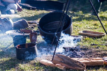 Homemade food in iron pot, a cauldron in smoke near dying embers, historical reenactment of Slavic...
