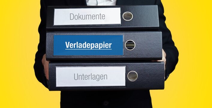 Verladepapier. Anwalt tr&auml;gt einen Stapel Ordner. 3 Aktenordner mit Text-Beschriftung. Hintergrund gelb.