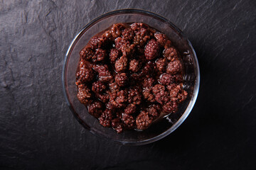 Blackberry jam in a plate on a dark background, top view