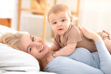 Obraz na płótnie Canvas Beautiful little baby boy layig on happy mother belly