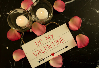 Be My Valentine, candles and rose petals with wooden sign.