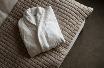 One White Bath Robe Laying On Bed Blanket Folded. Cotton Hotel SPA Clothing. Top View Clean...