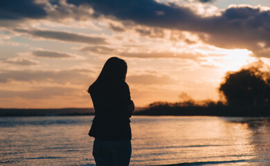 Silhouette of a young beautiful caucasian girl in jeans and a jacket against the backdrop of a...