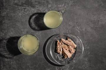 Homemade beef bone broth in clear glass cups on a dark gray background. bone broth with collagen content, which provides the body with amino acids and protein. The view from the top.