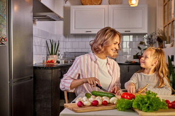 healthy food at home. happy caucasian family in the kitchen, mother and child daughter are preparing meal for dinner