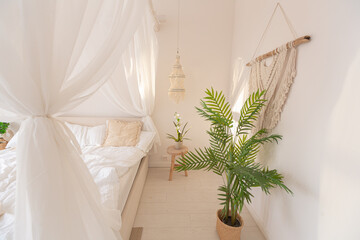 Cozy interior of a bright Balinese-style apartment with white walls, bamboo furniture. bed room with night lights, bed with balanchin and large windows © 4595886
