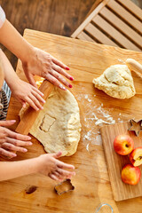 cropped mother teaches daughter prepare dough in the kitchen with fun, close-up photo of hands, top view