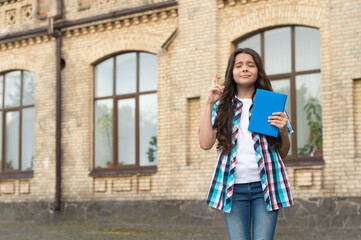 Ill keep my fingers crossed. Superstitious child make wish with closed eyes holding book. Following...