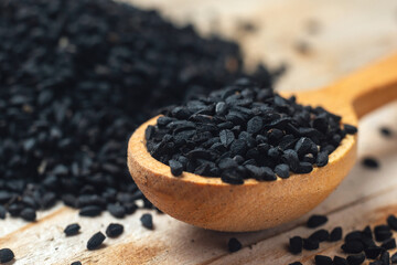 Fototapeta na wymiar Black cumin seeds on wooden spoon on wooden background