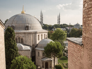 Fototapeta na wymiar Urban landscape of a Muslim city. Domes of mosques, towers of minarets. Blue sky, trees in green foliage. No people