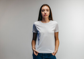 Obraz premium Stylish girl wearing white t-shirt posing in studio