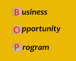 A picture of wooden block creating the word BOP or bussiness opportunity program on yellow background