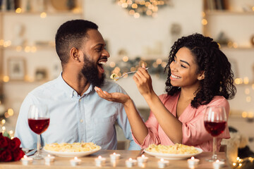 Smiling black woman feeding her man on a date