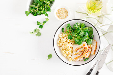 Grilled chicken breast, pasta and fresh lamb salad in lunch bowl. Top view
