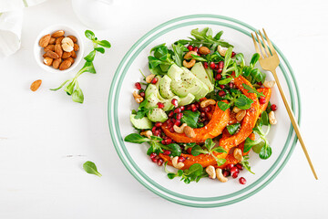 Fresh vegetable salad with lambs lettuce, baked butternut squash or pumpkin, avocado, pomegranate, cashew and almond nuts. Healthy vegetarian food concept. Top view