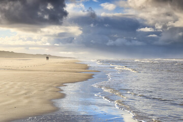 couple walking on sunny stormy beach