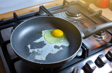 Fried egg on the pan. Preparing breakfast on the gas stove in the kitchen.