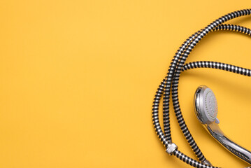 Shower head and water hose on the yellow flat lay background with copy space.