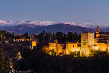 Alhambra palace in Granada at night with snow in the mountains in the back from San Nicolas lookout