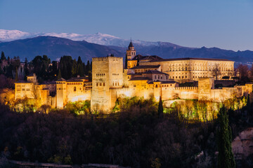 Alhambra palace in Granada at night with a little of snow in the mountains in the back from San Nicolas lookout