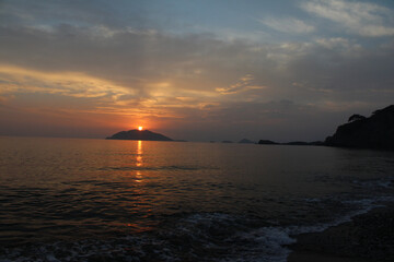 Colorful clouds, blue sky, sunset, sea and island silhouettes.