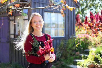 Woman Gardener in a Cottage Garden Holding Flowers in front of Shed