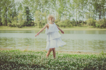 wild dance of cute child in green idyllic nature with river and meadow