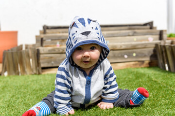 Simpática bebé jugando sentada en el jardin de casa con sudadera