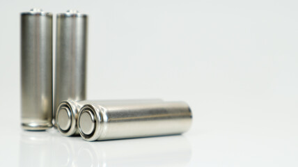 AA alkaline rechargeable batteries on white glossy background with reflection. Close up four empty batteries with copy space.