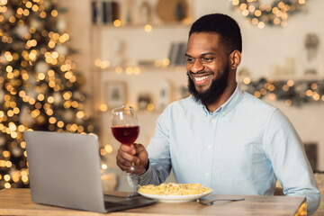 Fototapeta na wymiar Afro man having dinner during virtual date on laptop