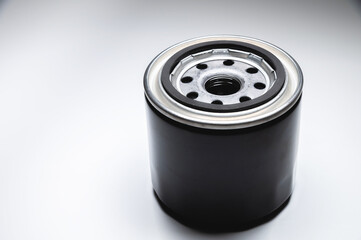 Black new oil filter in contrasting light on a black and white background. Wide angle