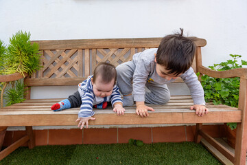 Simpáticos niños pequeños jugando en jardin de casa sentados en cesped
