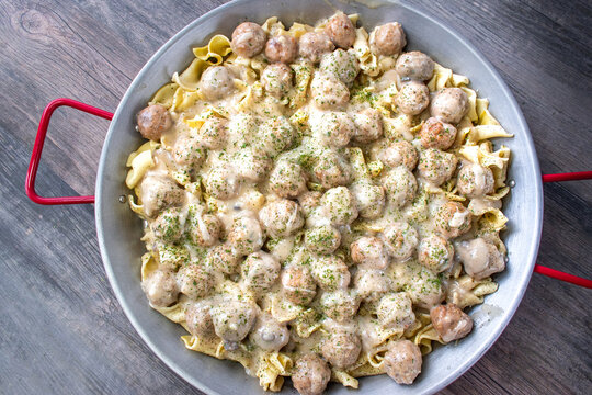 large pan of Swedish meatballs over noodles with cream sauce and parsley top view
