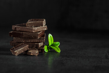 Stack of chocolate slices with mint leaf on a wooden table.Assortment of fine chocolates in white, dark, and milk chocolate. Sweet food photo concept.