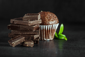 Chocolate cupcake with icing and chocolate bar in Dark lighting,Homemade delicious chocolate muffin on wooden background close-up
