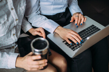 Two girls work side by side in the office on a laptop. Interaction of colleagues at work.
