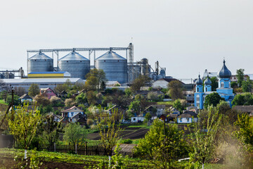Fototapeta premium Agricultural Silos. Storage and drying of grains, wheat, corn, soy, sunflower against the blue sky with white clouds.Storage of the crop